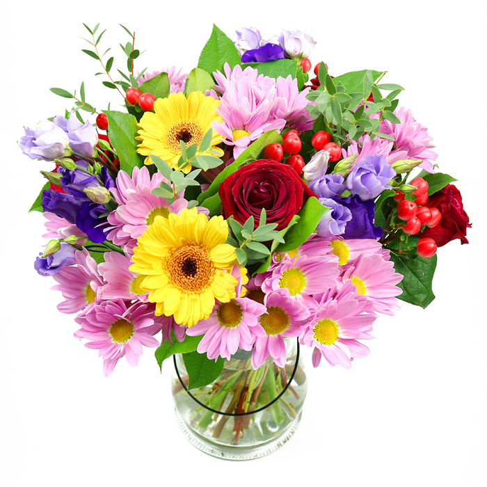 In this image, a beautifully composed bouquet bursts from a clear glass vase, its colours made even more striking by a plain white background. Deep red roses form the emotional core of the design, their velvety petals tightly layered in classic spirals that suggest warmth, love, and care. Close by, two bright yellow gerbera daisies with rich brown-orange centres beam confidently, bringing a joyful, almost sunshine-like quality that feels right at home in a welcoming South Croydon living room. Surrounding these star blooms, abundant pink and slightly lavender-tinted daisies or chrysanthemums spread outward, their multiple slim petals creating a feathery halo of softness, each bloom finished with a tiny yellow centre. Woven through this cushion of colour are elegant purple and soft lilac lisianthus, their slender, bell-shaped flowers and gently rolled edges lending the bouquet a refined, contemporary charm. Bright red hypericum berries cluster here and there like tiny ornaments, offering a rounded texture and a bold accent that plays beautifully against the petals. Various greens-broad, glossy leaves and finer, fresh green shoots-cradle the flowers, adding structure and a sense of garden freshness, reminiscent of a stroll through nearby parks and residential gardens in South Croydon. The transparent vase shows off the neatly trimmed stems aligned in clear water, a subtle sign of professional floristry. Soft, even light washes over the arrangement, highlighting the interplay of textures from velvety roses to smooth berries. The bouquet feels joyful yet composed, perfect for birthdays, thank-you gifts, or simply brightening a quiet corner of a South Croydon home.
